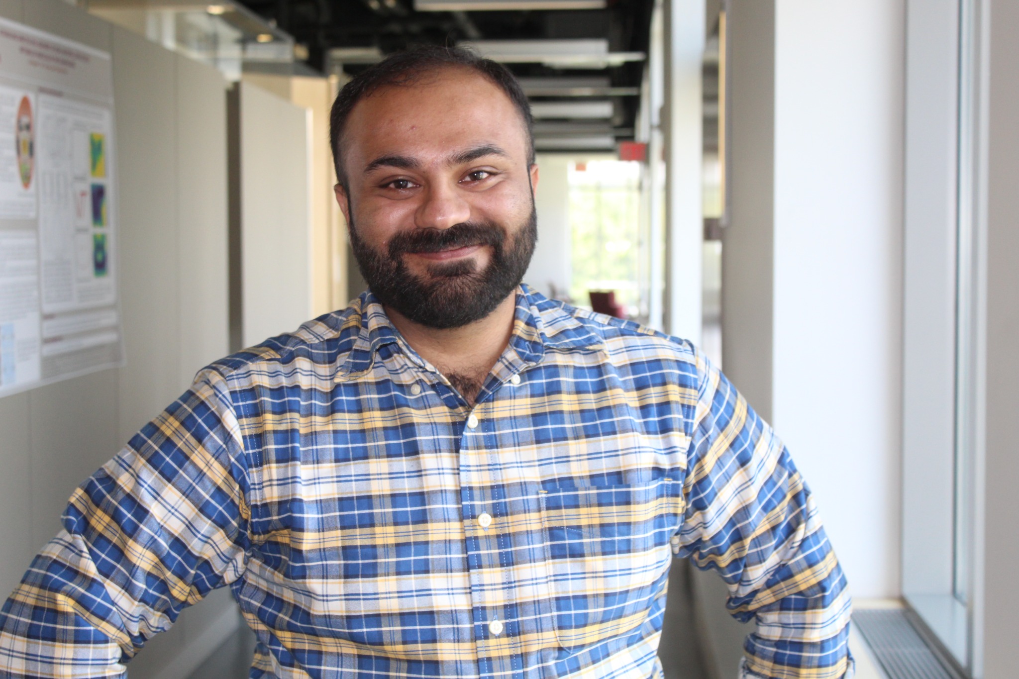 Emad Ali smiling in a university hallway